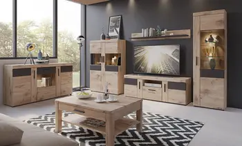 Wohnzimmer mit Wohnwand aus Eiche mit dunklen Absetzungen, Sideboard links, TV Lowboard und hohe Vitrinen, davor Couchtisch auf Zickzack Teppich.